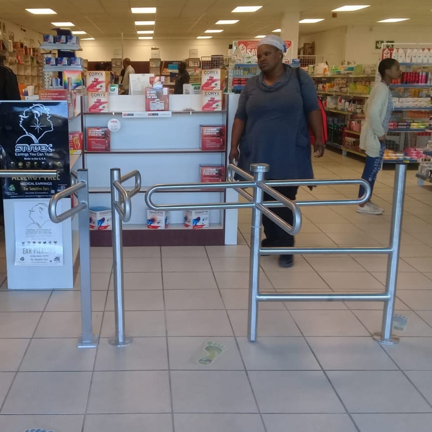 Shopper walking through a helicopter turnstile at the entrance of a retail store.