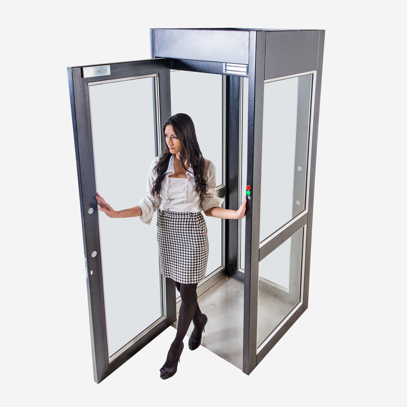 Woman stepping out of a black-framed mantrap cubicle through its open glass door.