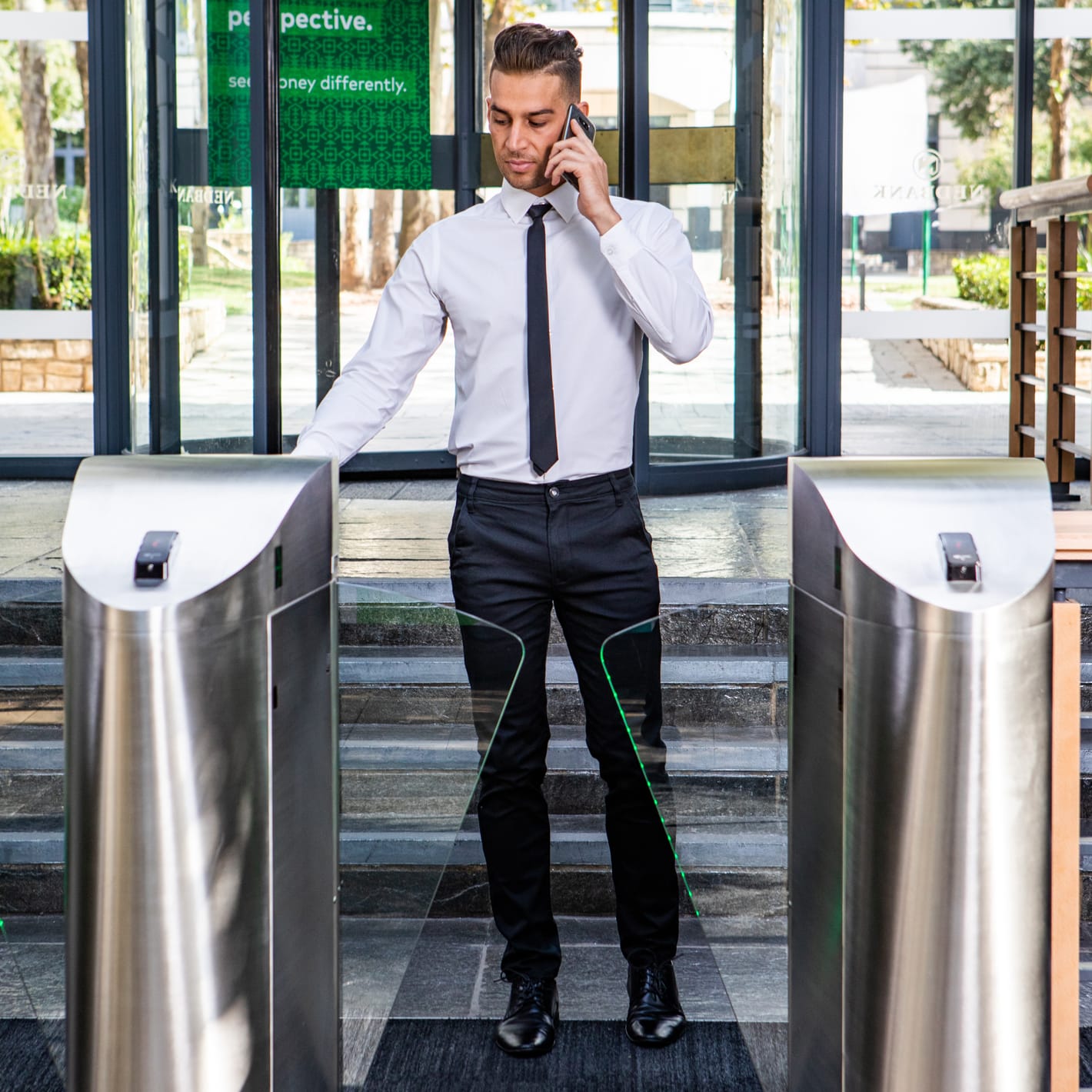A man on his phone walks through a Speedgate Express at a glass-fronted entrance.