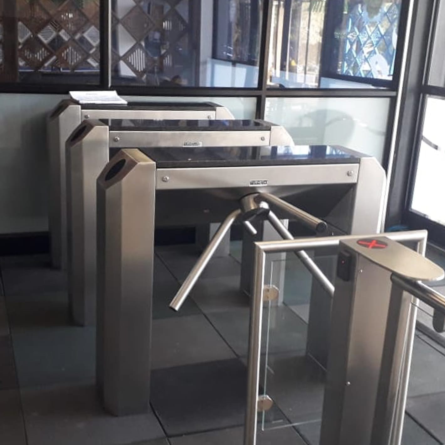 Row of stainless steel Streamline turnstiles with a glass screen in a building entrance.