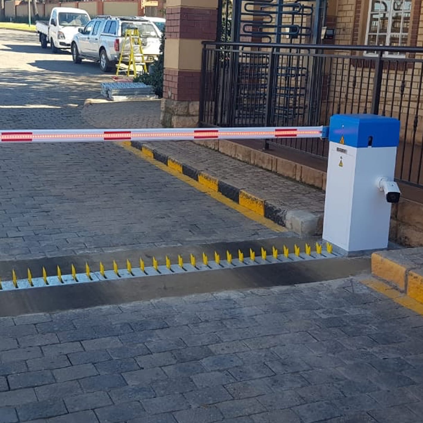 Talon Automatic barrier closing a paved entrance, with yellow spikes raised across the lane.
