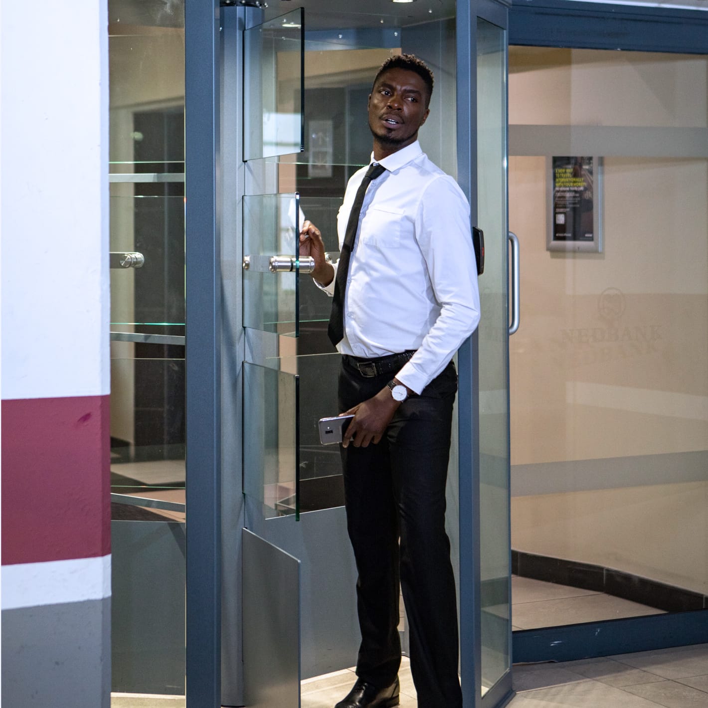Man presenting a card at a Triton octagonal turnstile set into a glazed reception entrance.