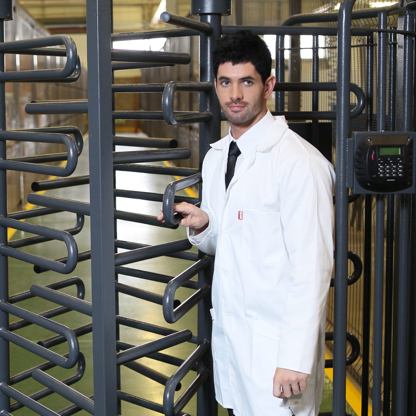 Man in a white lab coat passing through a Triumph turnstile next to a reader.