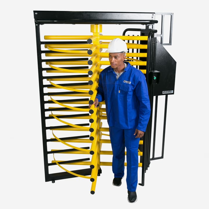 Worker in a hard hat walking through a Tribune turnstile with a yellow rotor and black frame.