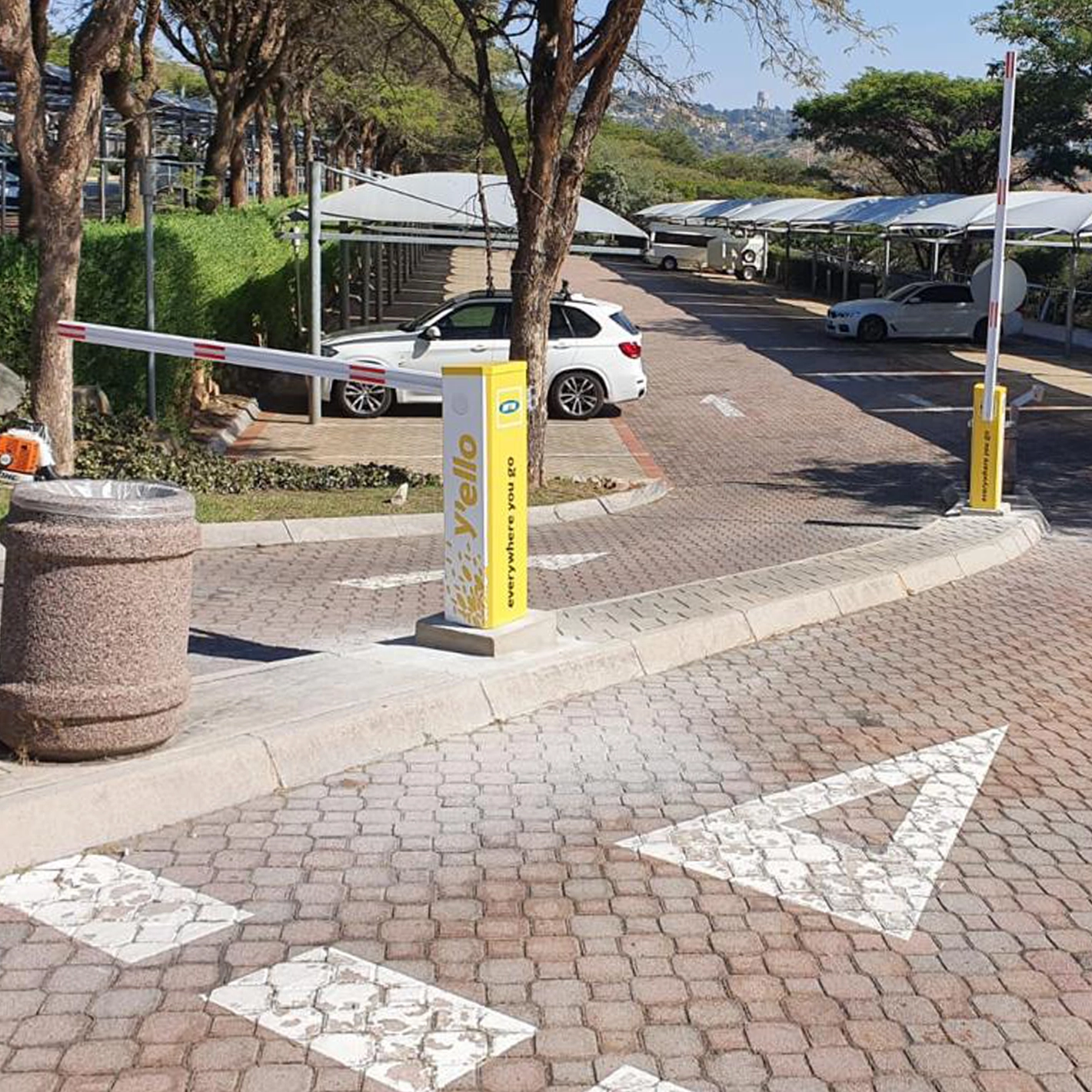 Yellow branded Velocity Nitro barrier at a paved car park entrance with a raised boom.