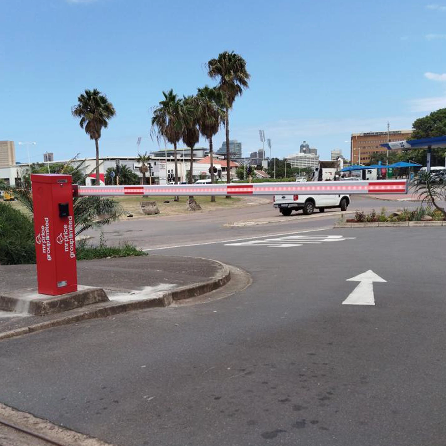 Red Velocity Nitro barrier on a road island controlling an exit lane lined with palm trees.