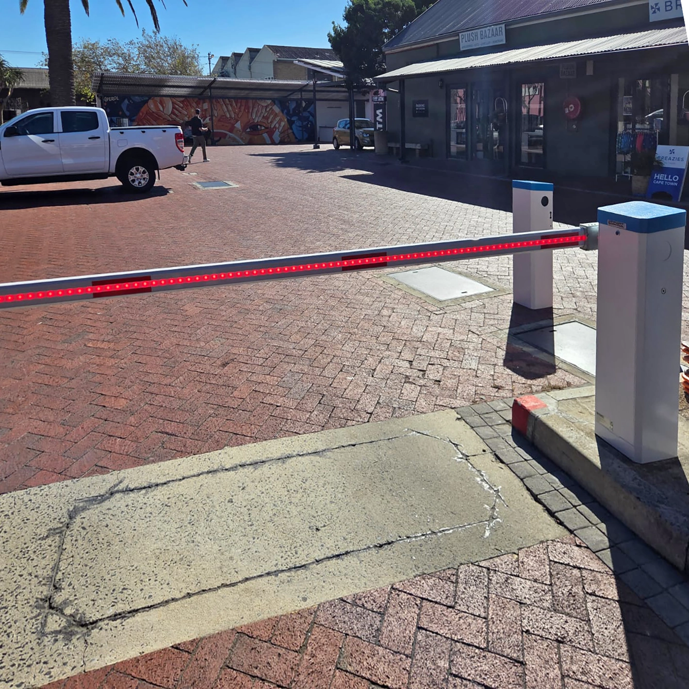 Velocity Nitro barrier closing a brick-paved entrance beside a row of shops.