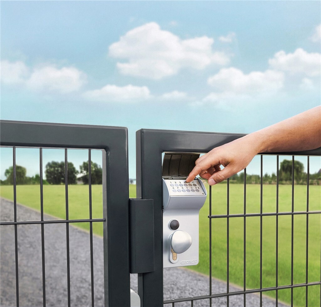 Hand entering a code on a Locinox Valentino lock on a gate