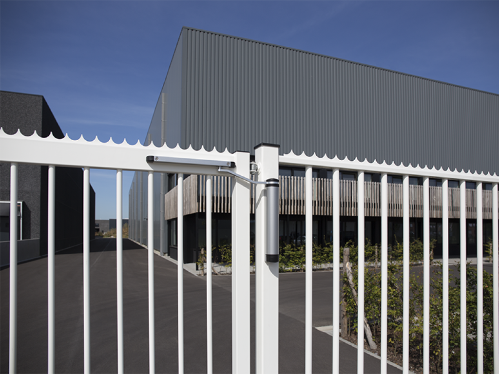Lion gate closer on a white vertical bar gate at a business site