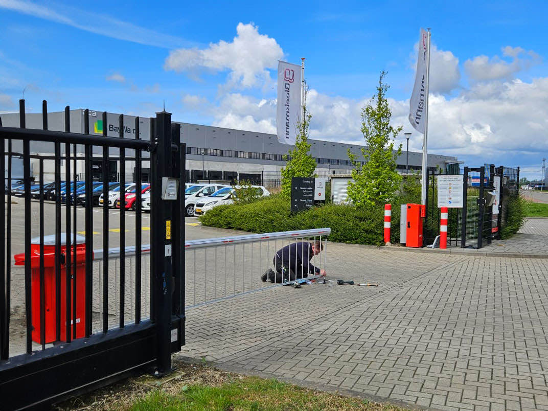 Contractor working at the entrance of a secured site with fence and barrier arm